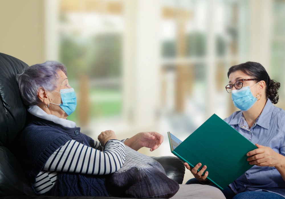 A female mature volunteer visits a single senior adult woman during a virus epidemic.